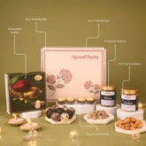 Gourmet gift set with various items including a box of chocolates, truffles, and cashews on a green background.